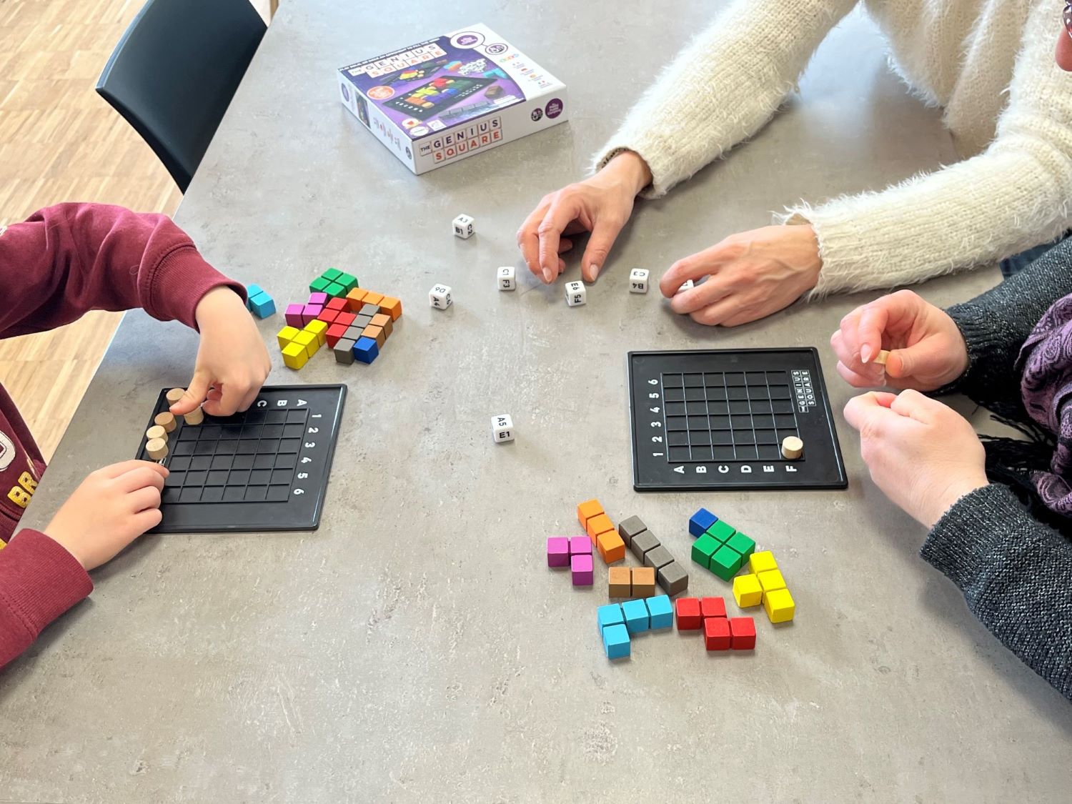 Un jeu de société manipulé par les mains de 3 personnes