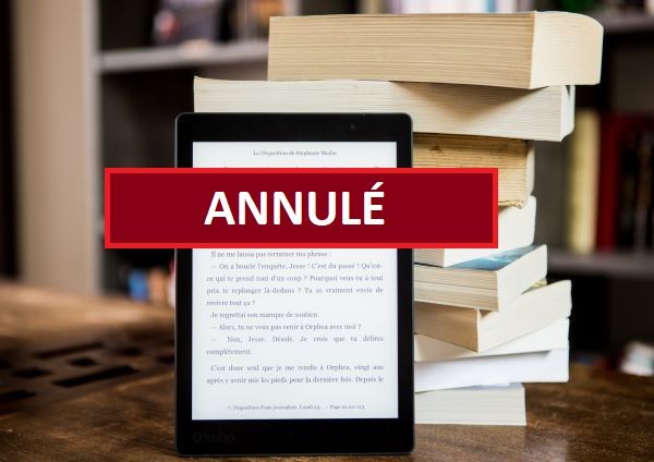 Une liseuse allumée avec une pile de livres derrière